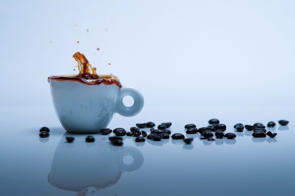 Ein Glas Kaffee und schwarze Körner auf dem Tisch