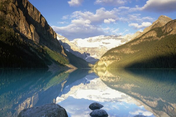 Las nubes y las montañas se reflejan en el cuerpo de agua