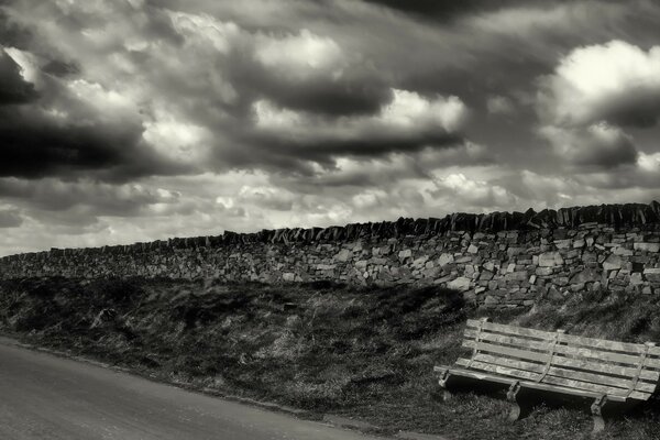 Black and white photo with a bench and a road