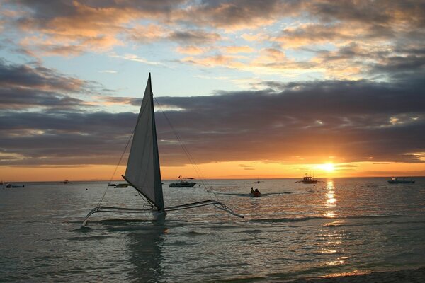 Yate en el fondo de la puesta de sol del mar