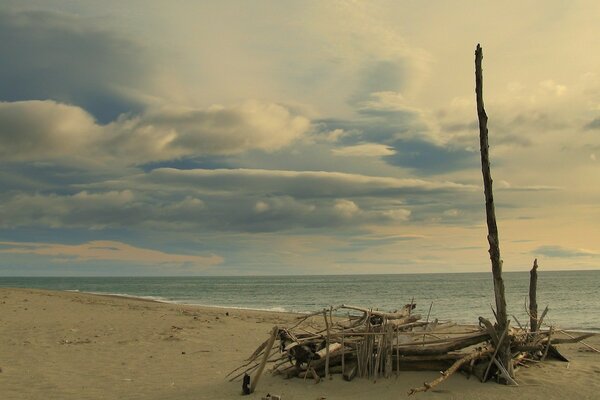 Am Strand liegen Trümmer hinter dem Meer und Wolken