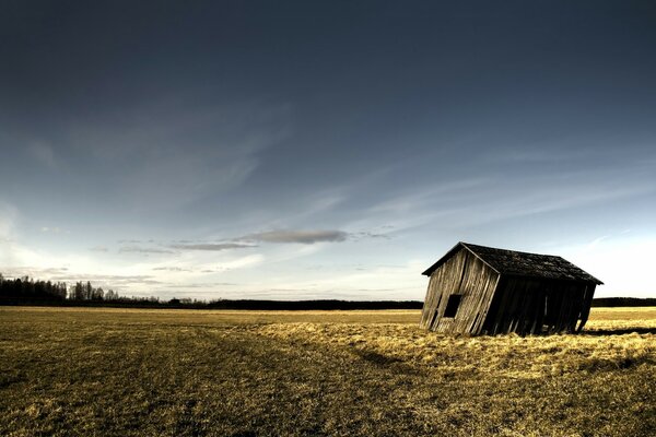 A lonely barn in a field against the background of clouds