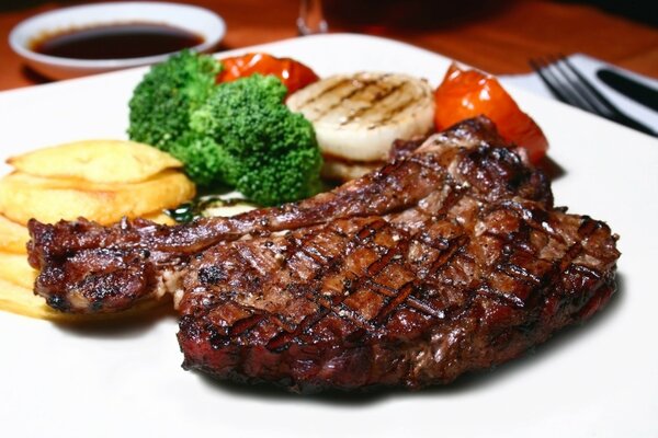 Bistecca di maiale su un piatto bianco con verdure