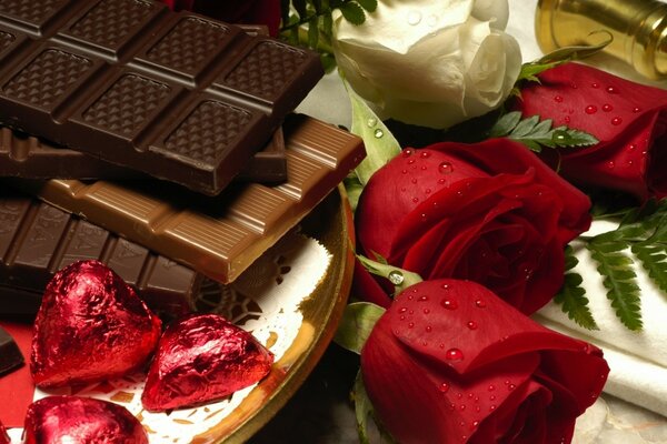 Chocolates, barras de chocolate junto a un ramo de rosas