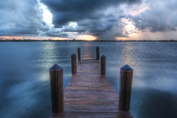 Pier on the lake against the background of clouds