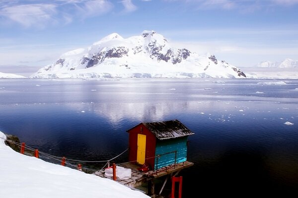 A house on the snowy shore near the mountains