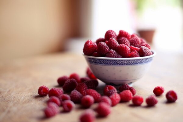 Framboises dans une assiette sur une table en bois