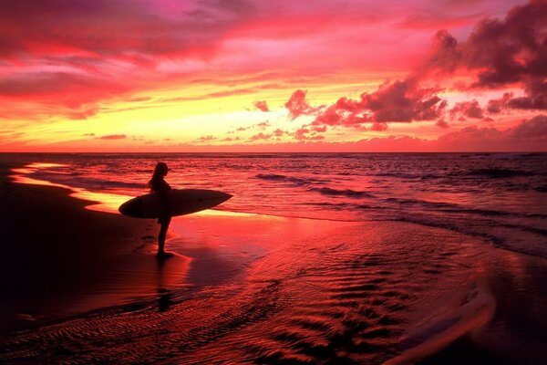 Mädchen Surfer steht bei Sonnenuntergang am Meer