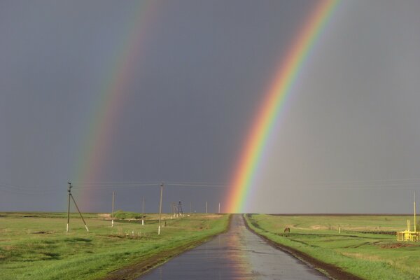 Doppelter Regenbogen auf der Straße im Feld