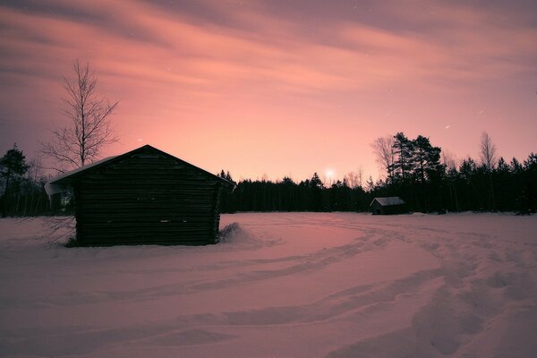 A lonely house among a snowy landscape at sunset