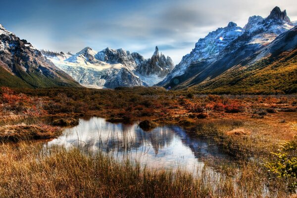 Las montañas con nieve azul se reflejan en un charco