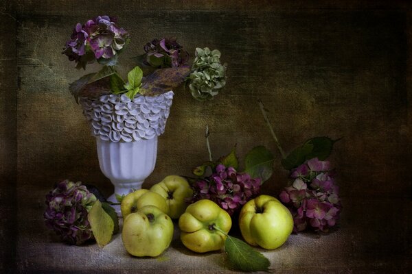 Apples with flowers in a vase on the table