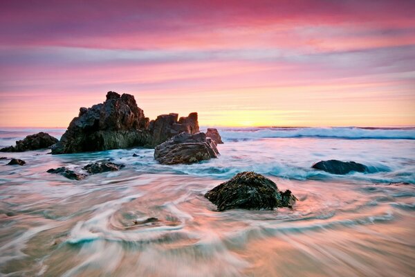 Alba sulla spiaggia di sabbia con le pietre