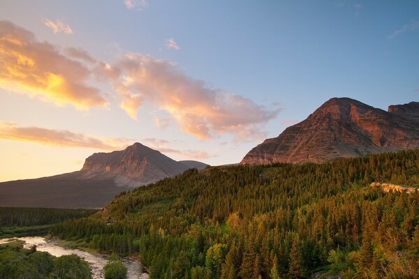 Paesaggio di montagne e alberi su uno sfondo di nuvole al tramonto