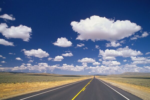 White clouds, clouds in a blue sky, a long road