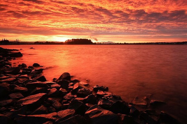 Roter Sonnenuntergang. Das felsige Ufer des Sees