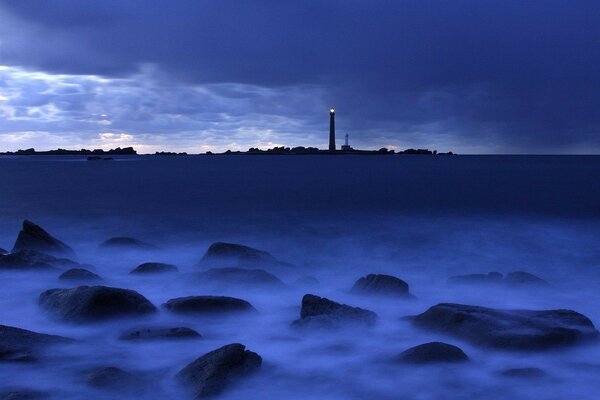 Pietre nella nebbia e un faro in lontananza