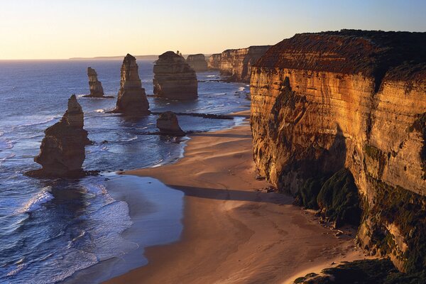 Cliff by the sea, waves by the rocks, the sea is blue