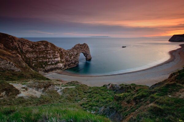 Sonnenuntergang vor dem Hintergrund des Meeres und der Felsen in England