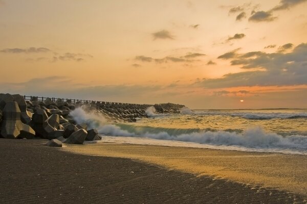 Waves beat against the pier at sunset