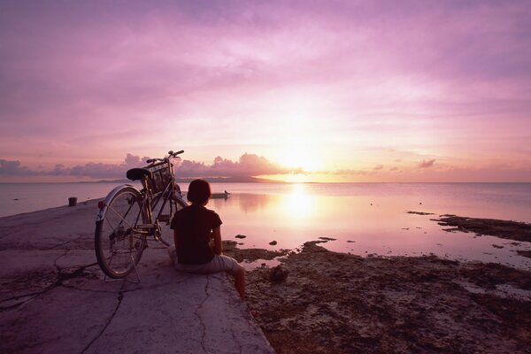 A dreamy girl admires the sunset on the sea