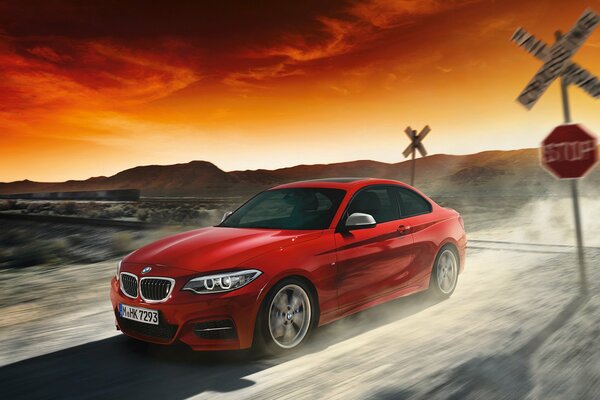 Voiture BMW rouge sur fond de coucher de soleil