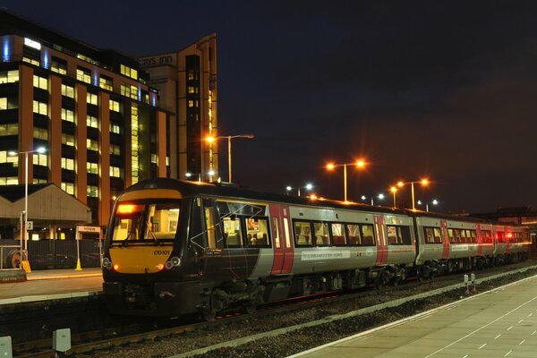 Tren de pasajeros en la plataforma con luces nocturnas