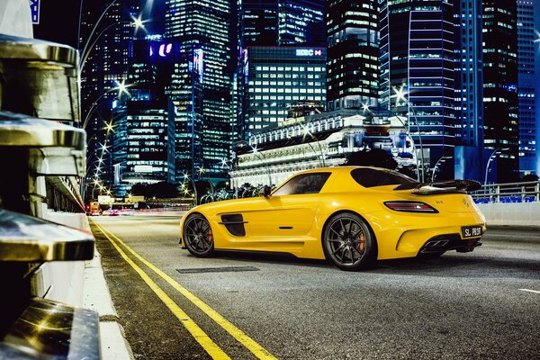 Mercedes jaune sur fond de gratte-ciel de la ville de nuit