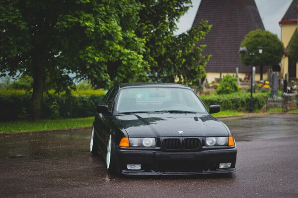 Black legendary bmw e36 among private houses