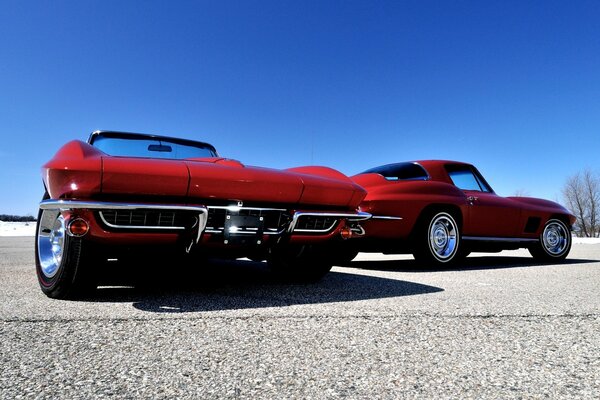 Zwei rote Chevrolet Corvette auf einem blauen Himmelshintergrund