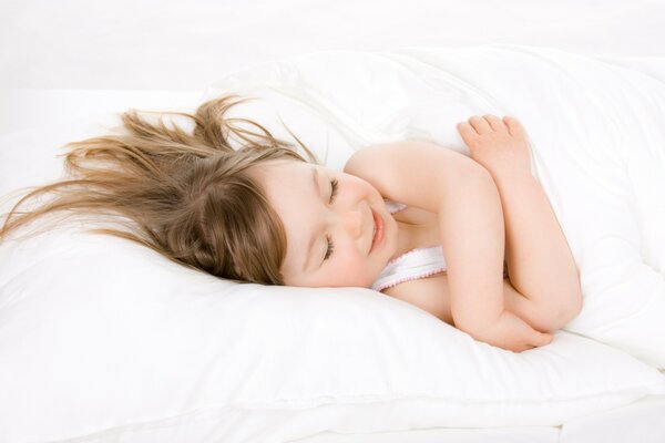 Un niño en una almohada blanca sonríe mientras duerme