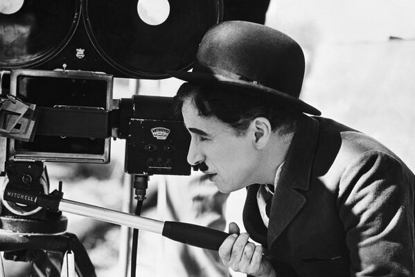 Charles Chaplin with a mustache in a bowler hat looks at the camera