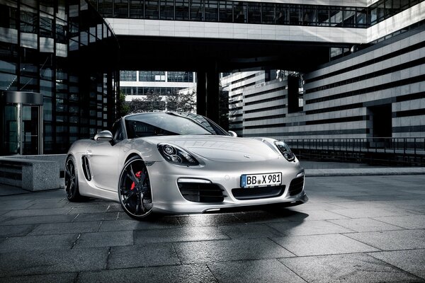 A silver Porsche convertible stands on the building