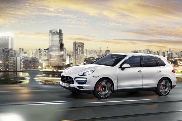 Une Porsche Cayenne légère se précipite sur la route sur le fond de la ville