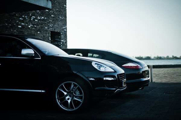 Ein schicker schwarzer Porsche Cayenne, der vor einem Backsteingebäude geparkt ist