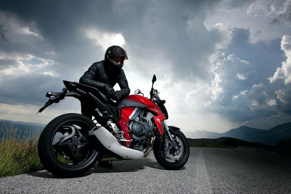 Motorcyclist on the side of the road against the background of clouds