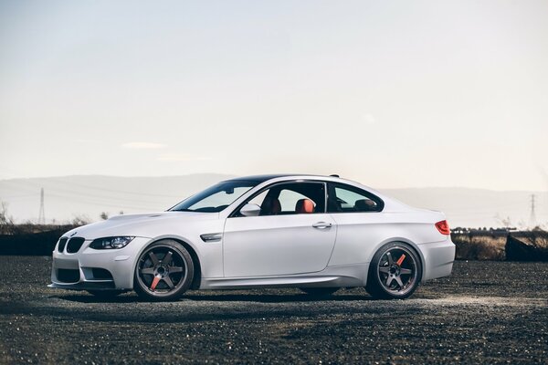 White BMW sideways on a light sky background