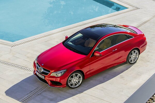 Hermosa foto de coche. Foto de la máquina desde arriba. Mercedes. Coche cerca de la piscina. Es un coche caro . Coche rojo. Máquina para niña