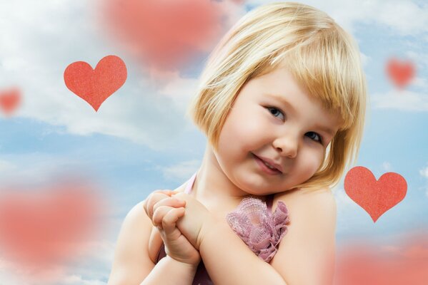 A little girl smiles against the background of hearts