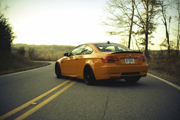 The orange car is standing on a flat road