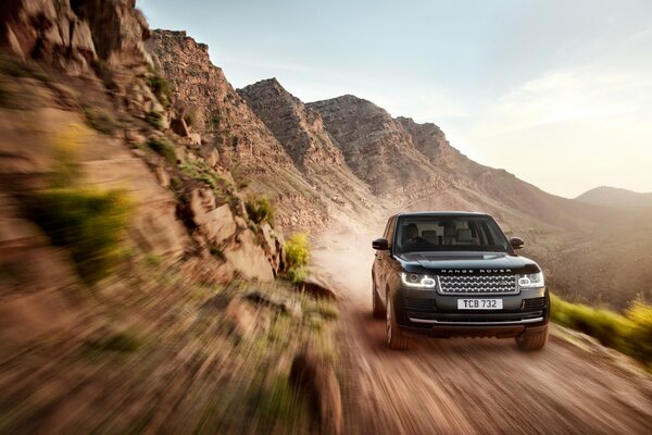 Black Land Rover auf einem Feldweg, umgeben von Felsen