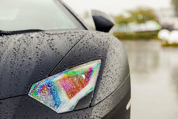 Ein nasser Lamborghini aventador. Scheinwerfer in Regenbogentropfen