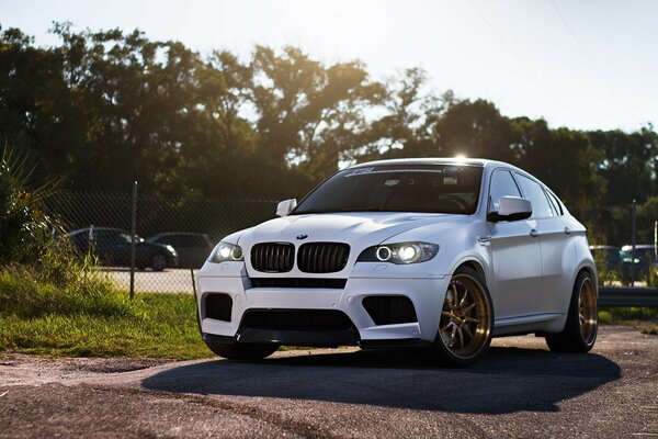 Une BMW blanche projetant une ombre sur la route