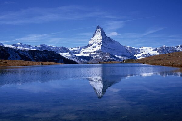 Un enorme montagna innevata si riflette nel lago