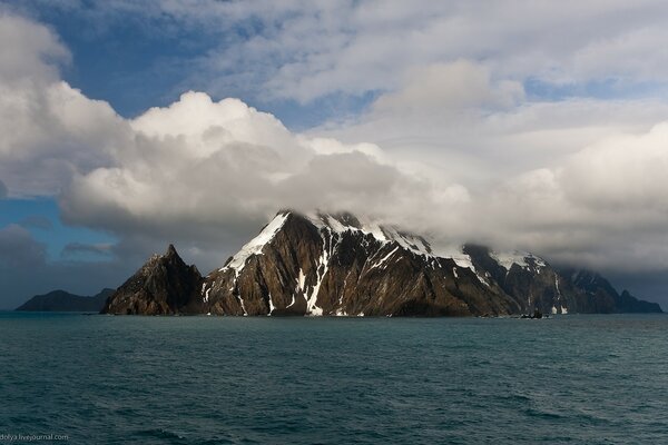 There is a huge rock in the sea in the fog