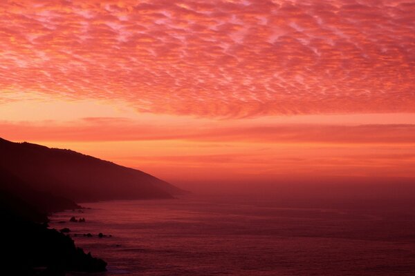 A bright fiery Sunset on the horizon, merges with the sea