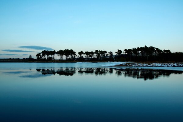 The trees on the island are reflected in the water