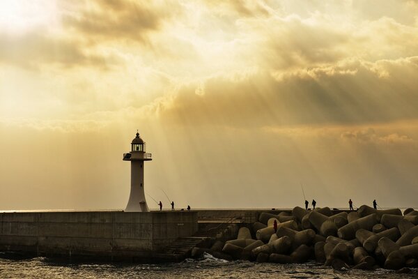 Faro bajo el sol y pescadores