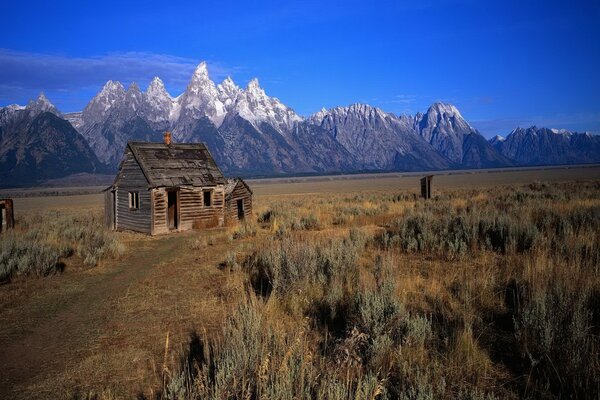 An abandoned hut in the steppe against the background of mountains