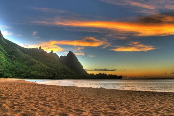 Strand bei Sonnenuntergang vor dem Hintergrund der Berge und des Meeres